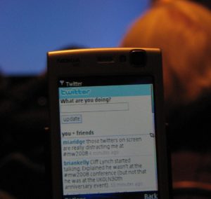 2008-era Nokia phone with a tweet on the screen: @miaridge 'those twitters on screen are really distracting me at #mw2008'